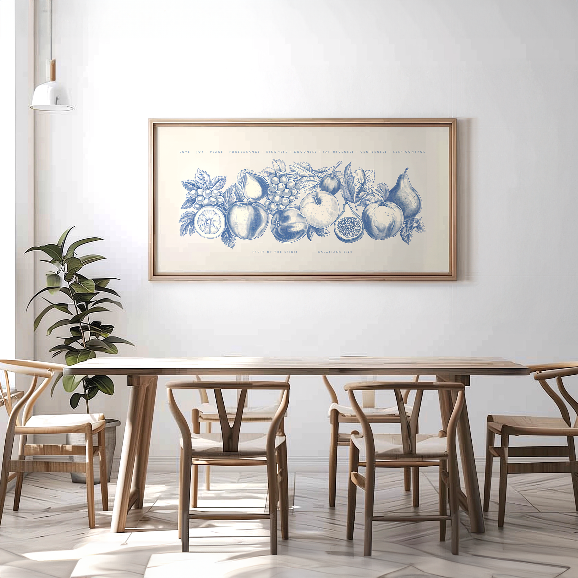 Large Fruit of the Spirit wall art in blue, Galatians 5:22 Christian print framed in a minimalist dining room with light wood furniture and white walls.